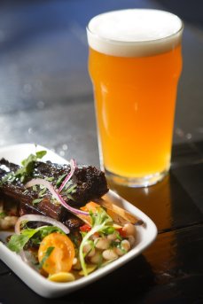 Smoked honey glazed goat ribs with a Mediterranean salad, paired with Quinn's Ale, is one of the rotating happy hour choices at Quinn's Pub on Capitol Hill in Seattle on Tuesday, Sept. 22, 2015.